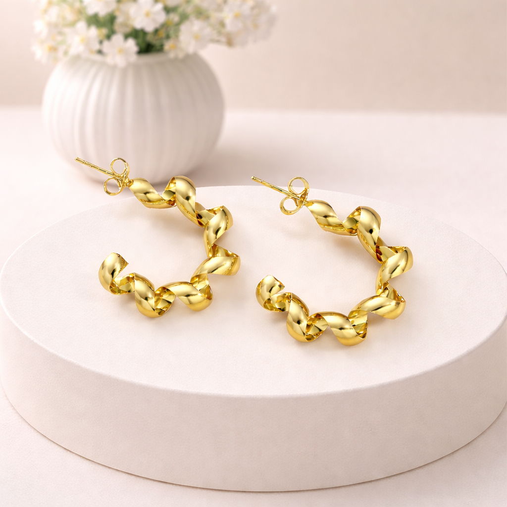 Gold spiral stud earrings with a glossy twisted ribbon design, displayed as a pair on a white platform.