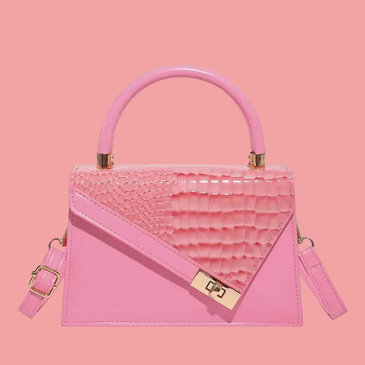 Small pink handbag with textured flap detail, top handle, and detachable strap, displayed on a pink background.