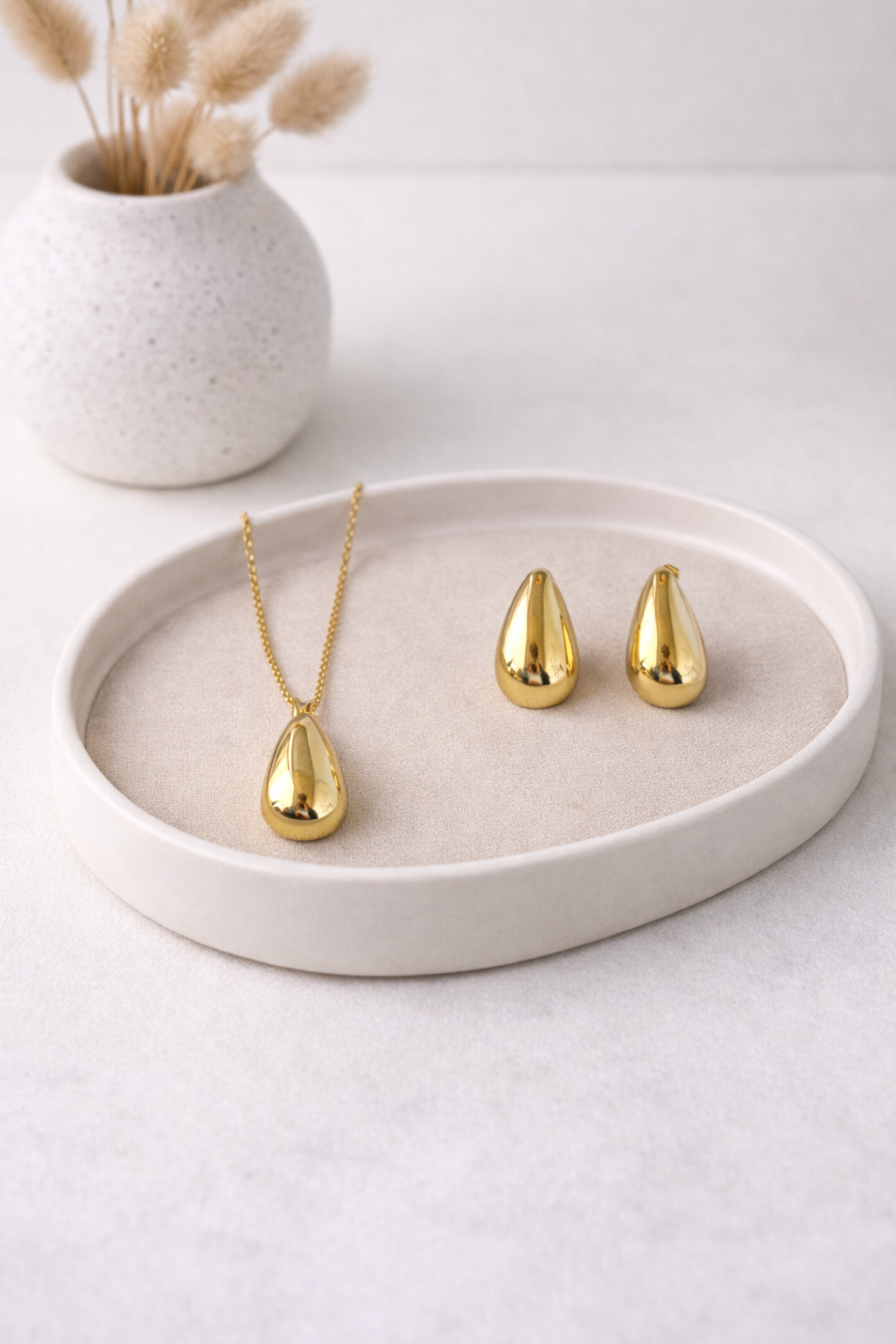 Golden Drop Necklace & Earrings Set with polished teardrop shapes displayed on a light beige tray.