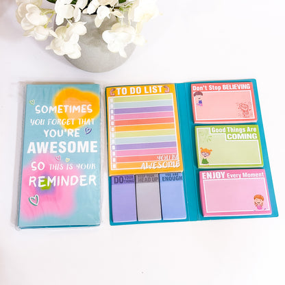 Foldable sticky notepads with motivational messages, including a to-do list, on a turquoise base.