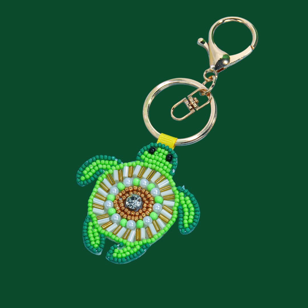 Green beaded turtle bag charm with gold-tone hardware, featuring white, gold, and light green shell details and a central rhinestone.