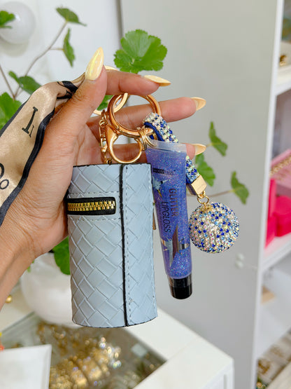 Light blue woven coin purse combo set featuring a gold zipper, purple glitter lip gloss, and blue and silver rhinestone ball charm on a gold keyring, held by a hand.