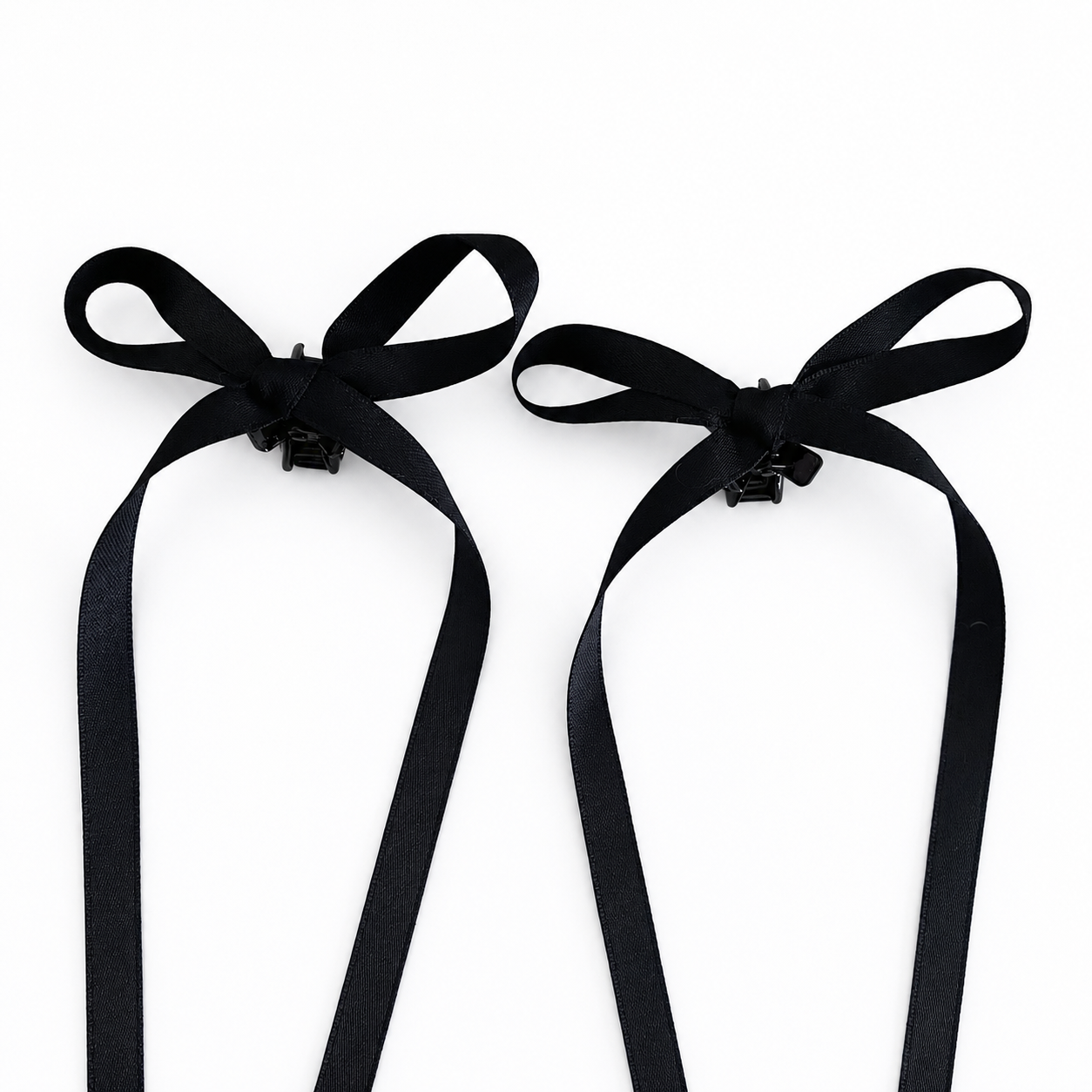 A set of two black bow mini hair clips with long satin ribbons on a white background.