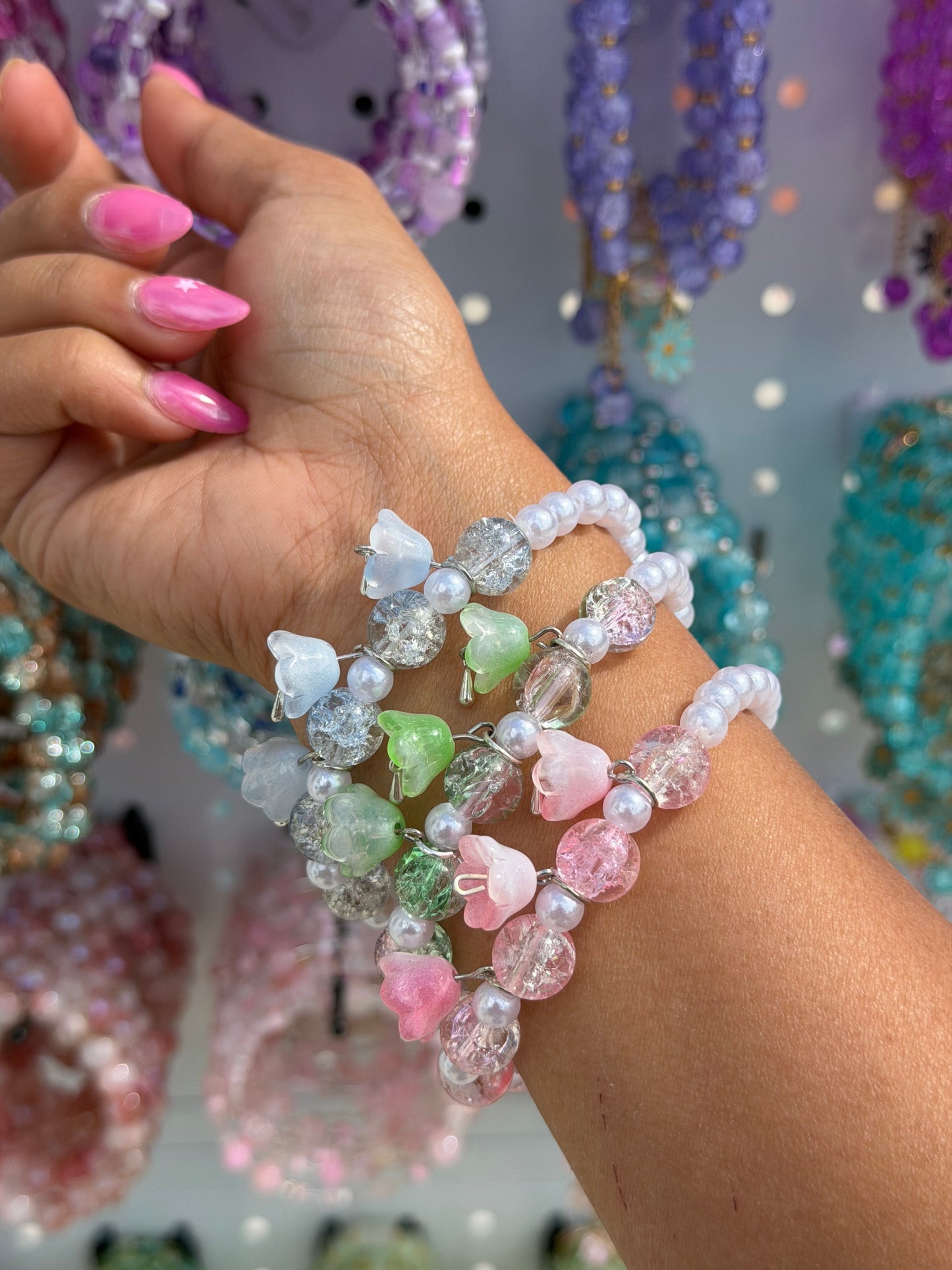 Four Tulip Lucky Charm Pearl Beaded Bracelets with pastel tulip charms and cracked glass beads on a hand with pink nails.