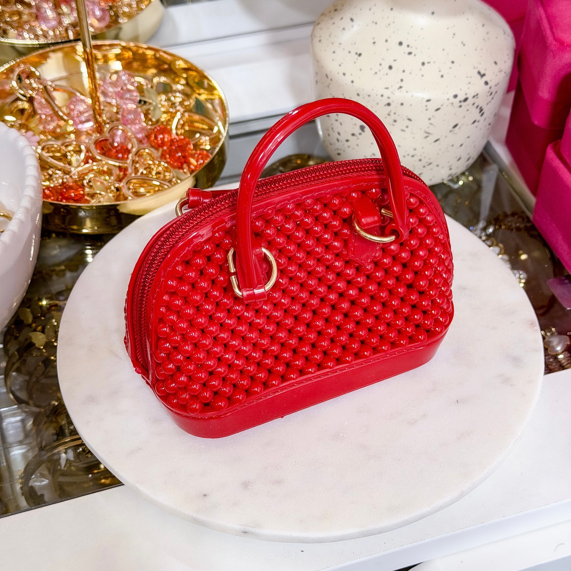 Red beaded dome chain bag from vendor, displayed on marble stand