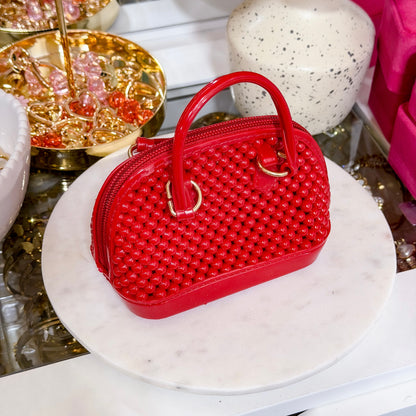 Red beaded dome chain bag from vendor, displayed on marble stand
