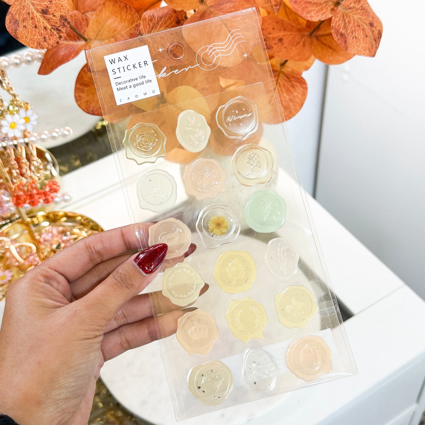 Decorative wax seal stickers by ZAOMO, held in hand, showcasing a variety of delicate floral and botanical designs.