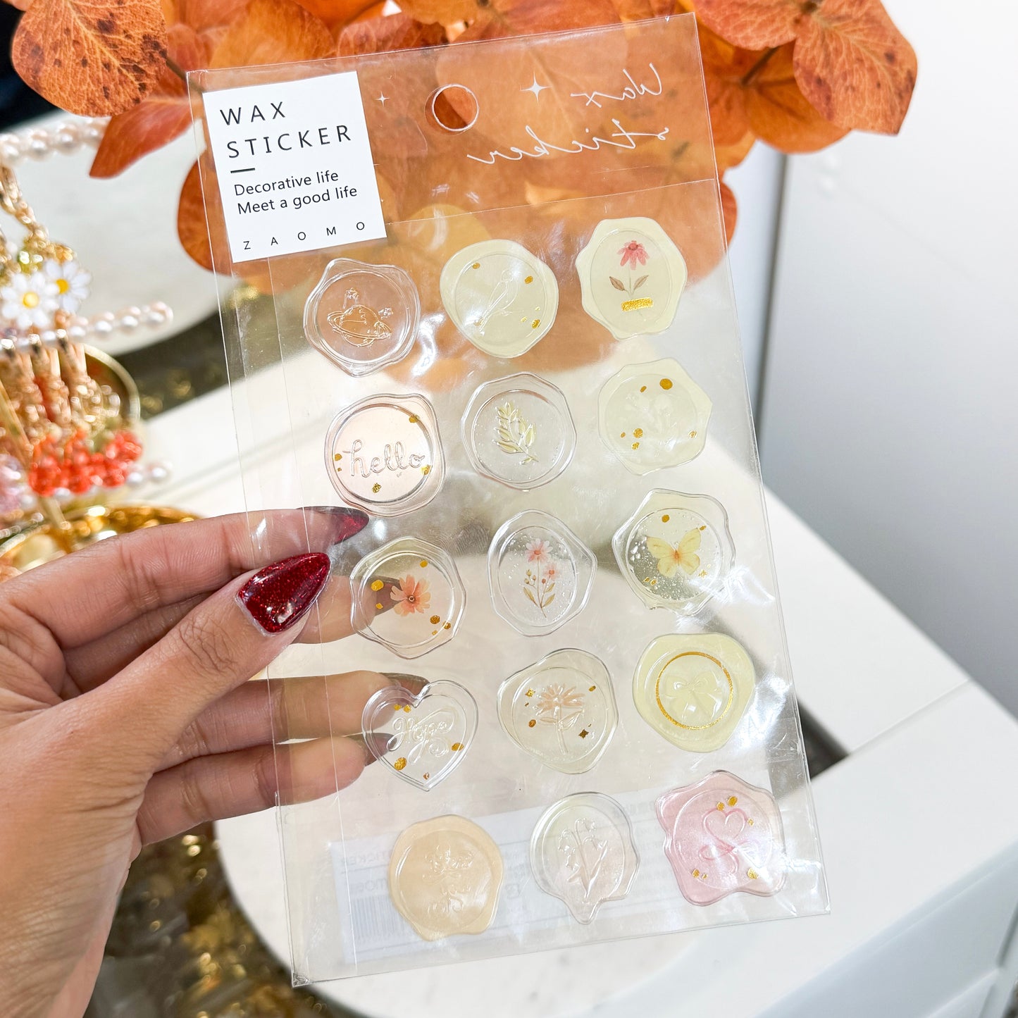 Decorative wax seal stickers by ZAOMO, featuring various botanical and celestial motifs on a clear plastic sheet.
