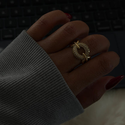 Close-up of a hand wearing a gold ring with a blurred background