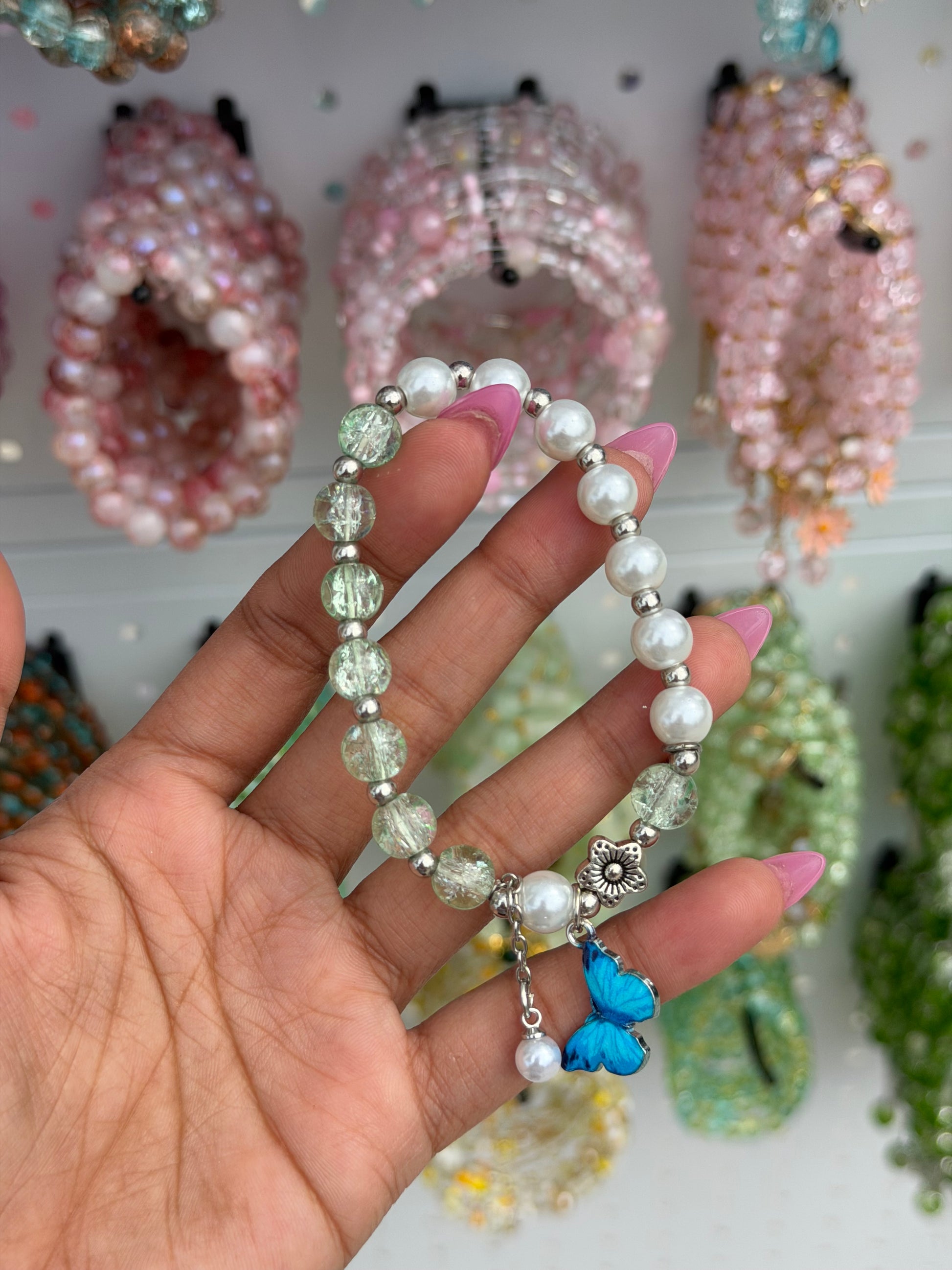 Butterfly Pearl Beaded Bracelet with cracked green glass beads and a blue butterfly charm, held by a hand.
