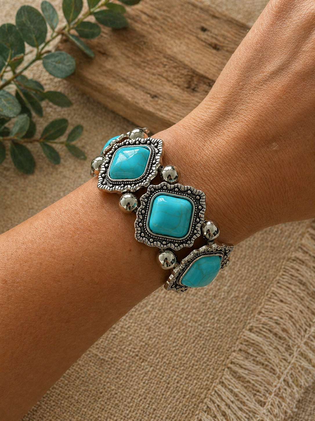 Chunky Bracelet with turquoise stones in ornate silver-tone settings, worn on a wrist against a rustic background.