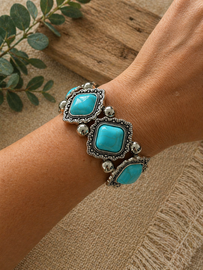 Chunky Bracelet with turquoise stones in ornate silver-tone settings, worn on a wrist against a rustic background.