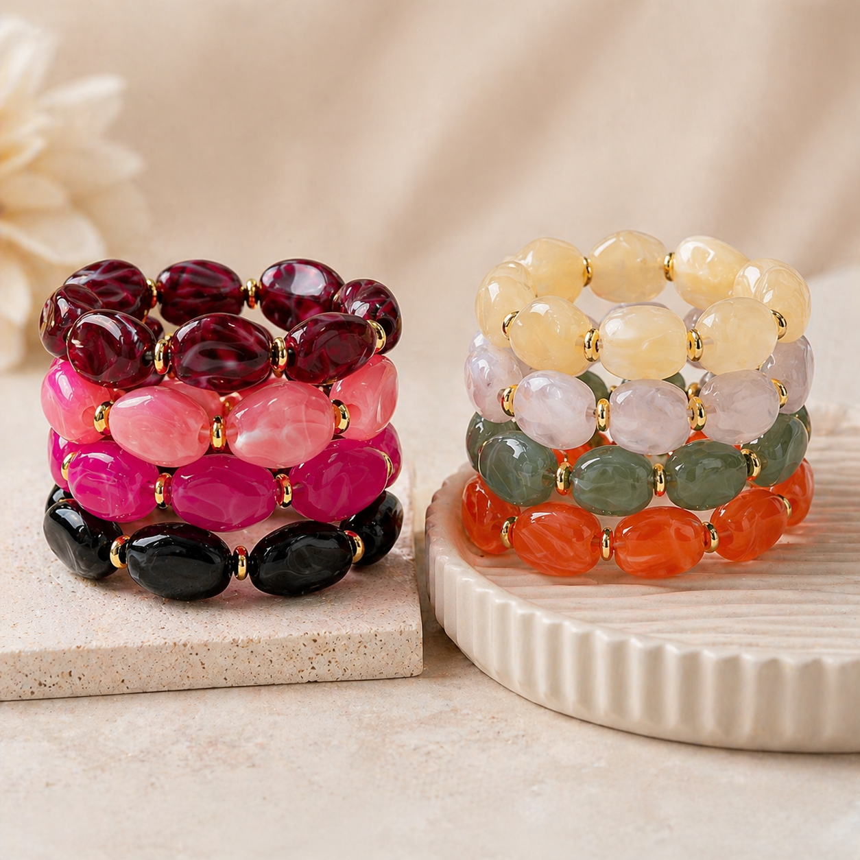 Stacked chunky bracelets with oval, polished beads in various shades of red, pink, black, yellow, green, and orange, separated by gold spacers.