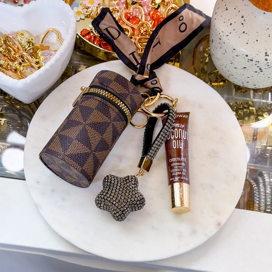 Brown geometric coin purse combo set with zippered coin pouch, coconut oil lip gloss, and star-shaped rhinestone keychain displayed on a white marble plate.