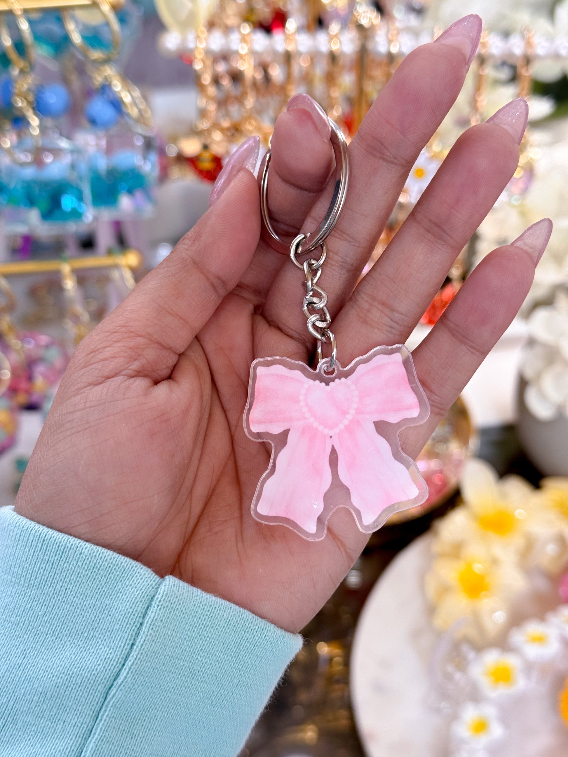 Pink bow keychain from a variety of styles, suspended from a silver keyring and chain.