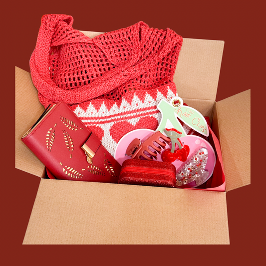 Red Valentine gift set displayed inside an open cardboard box showing a red knit tote, wallet, jewelry box, and hair clip set.