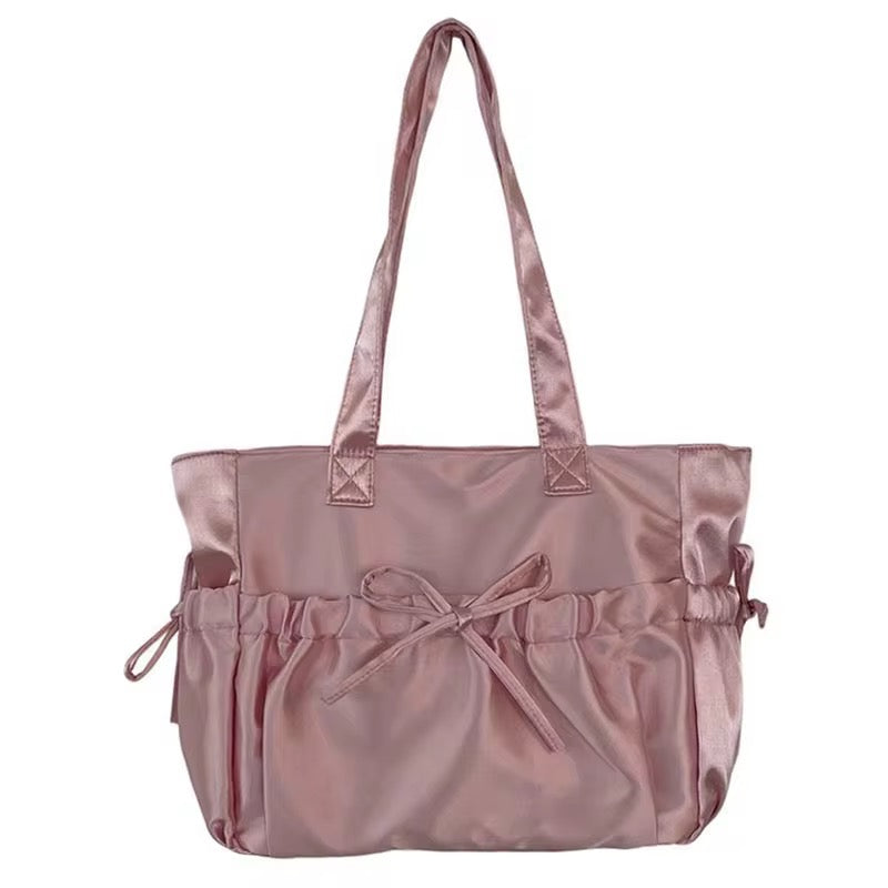 Pink satin tote bag with a bow by Coquette, featuring ruched detailing.