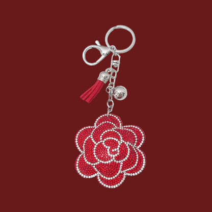 Red rose-shaped rhinestone keychain with silver hardware on a red background.