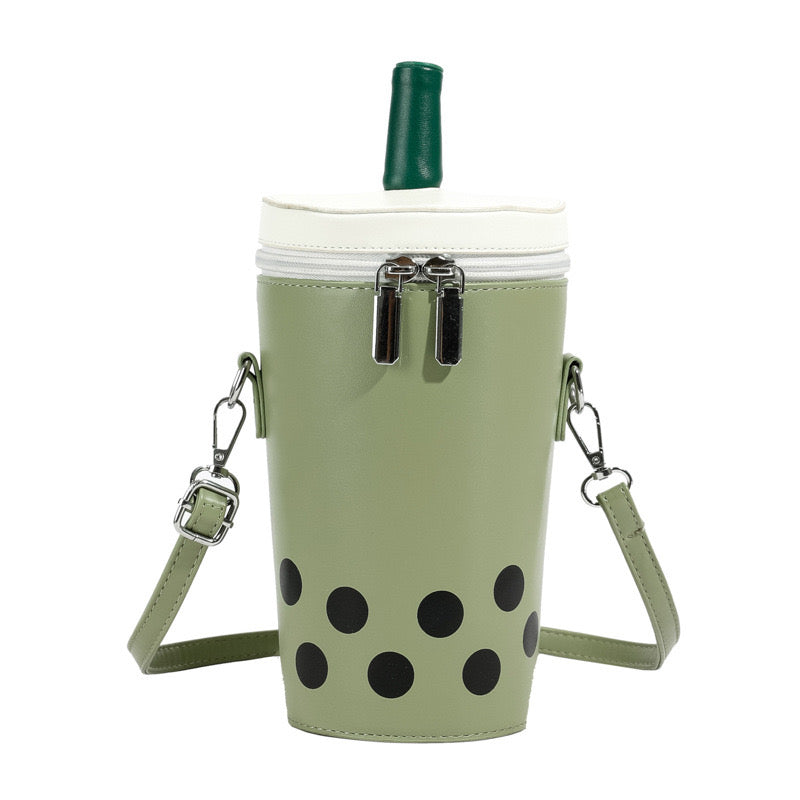 Green boba tea crossbody bag with a white lid, green straw, double silver zippers, and black polka dots, featuring an adjustable strap.