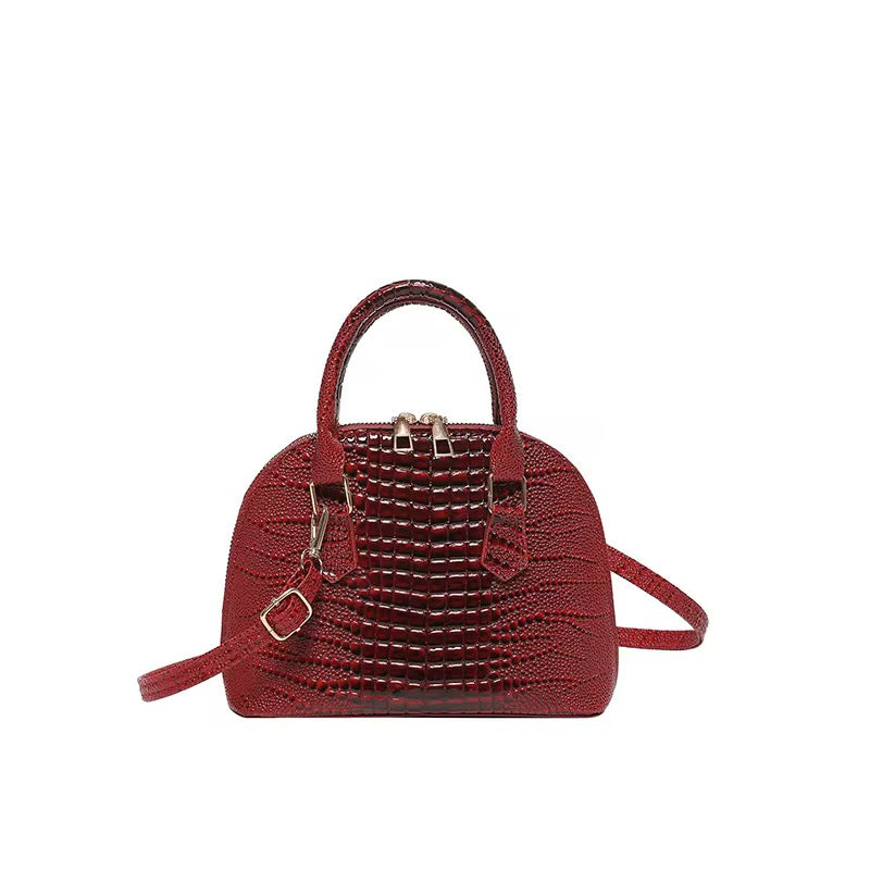 Red dome crossbody bag with an alligator texture.