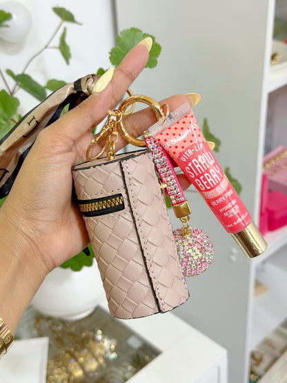 Light pink woven coin purse combo set featuring a strawberry lip gloss, sparkling rhinestone charms, and a patterned ribbon, held in hand.