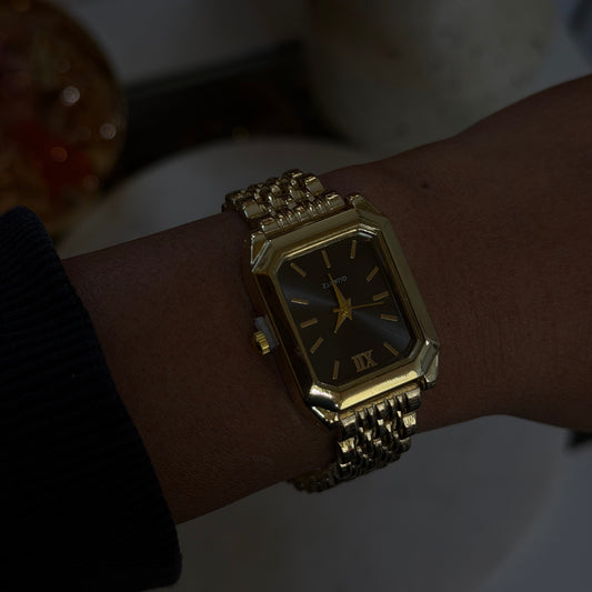 Gold wristwatch on a wrist with a blurred background
