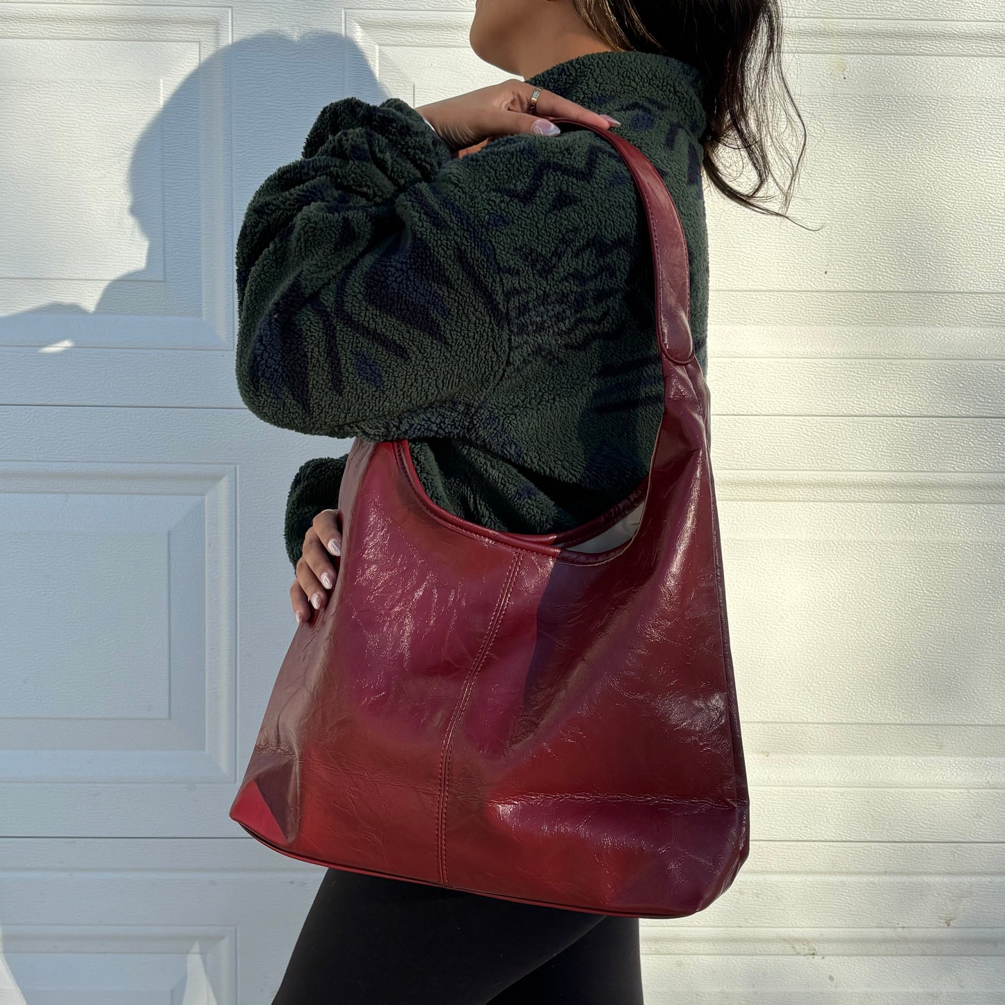 Red leather tote bag by Hobo with a textured finish, styled with a green fleece jacket and black leggings.