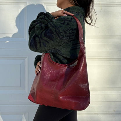 Red leather tote bag by Hobo with a textured finish, styled with a green fleece jacket and black leggings.
