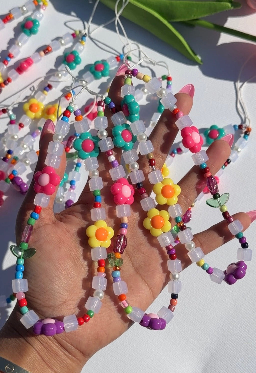 Daisy Dream Phone Strap featuring colorful beads, translucent cubes, and vibrant flower charms held in a hand.