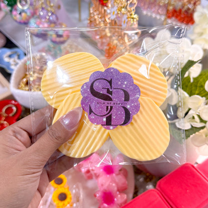 Yellow chip bag clip set from Stir of Beauty, held in its packaging, with a purple glitter logo sticker.
