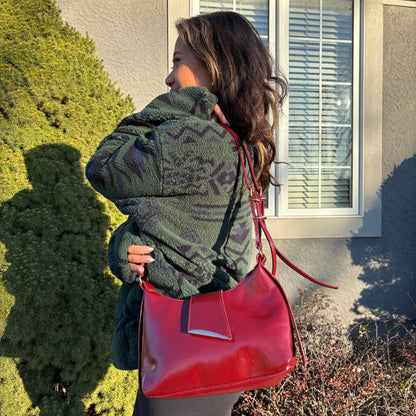 Red leather shoulder bag by unknown brand with a silver accent, worn with a patterned fleece jacket.