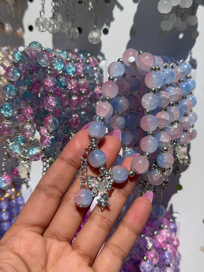 Blue beaded bracelets with round pastel blue and pink beads, silver spacers, and a butterfly charm.