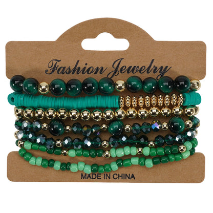 Bohemian style layered bracelets with various green and gold beads displayed on a kraft tag.