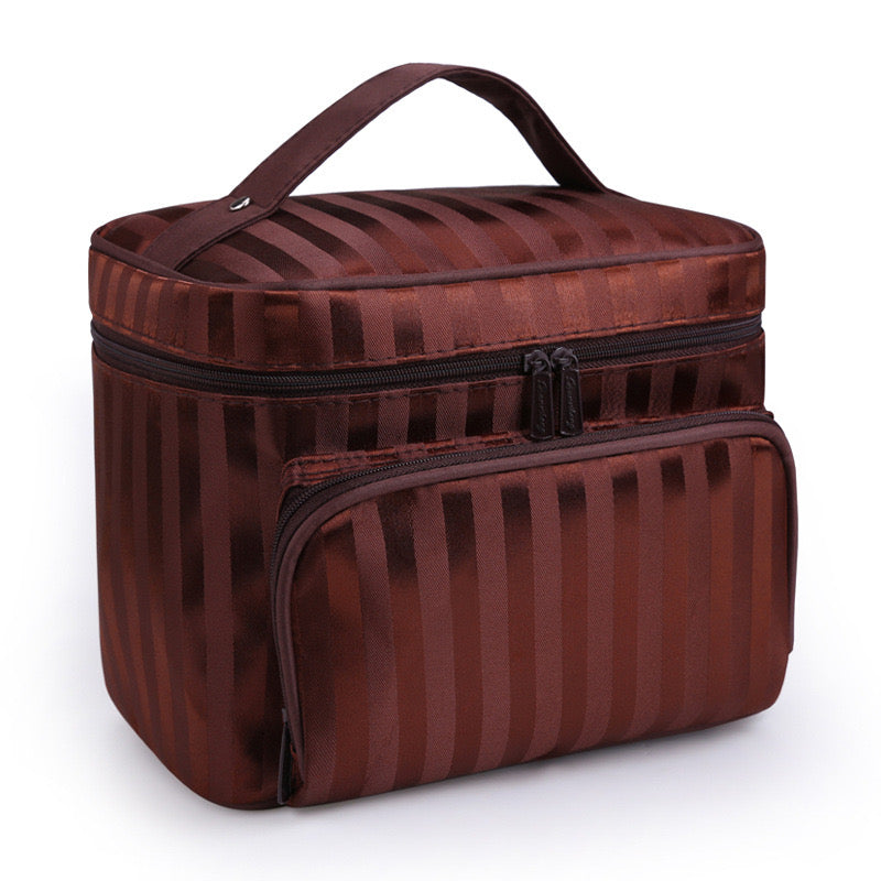 Brown makeup bag by Bella with vertical stripes, a top handle, and a front zippered pocket.