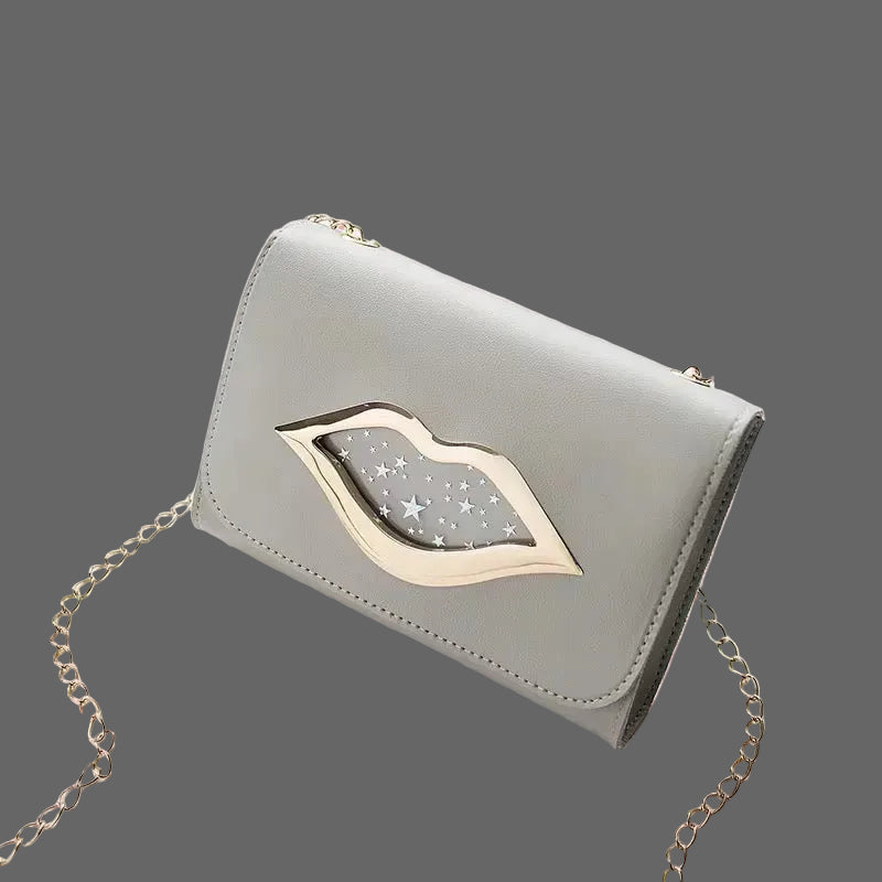 Grey clutch-style handbag with silver chain strap and lip-shaped metal accent, displayed on a Grey background.