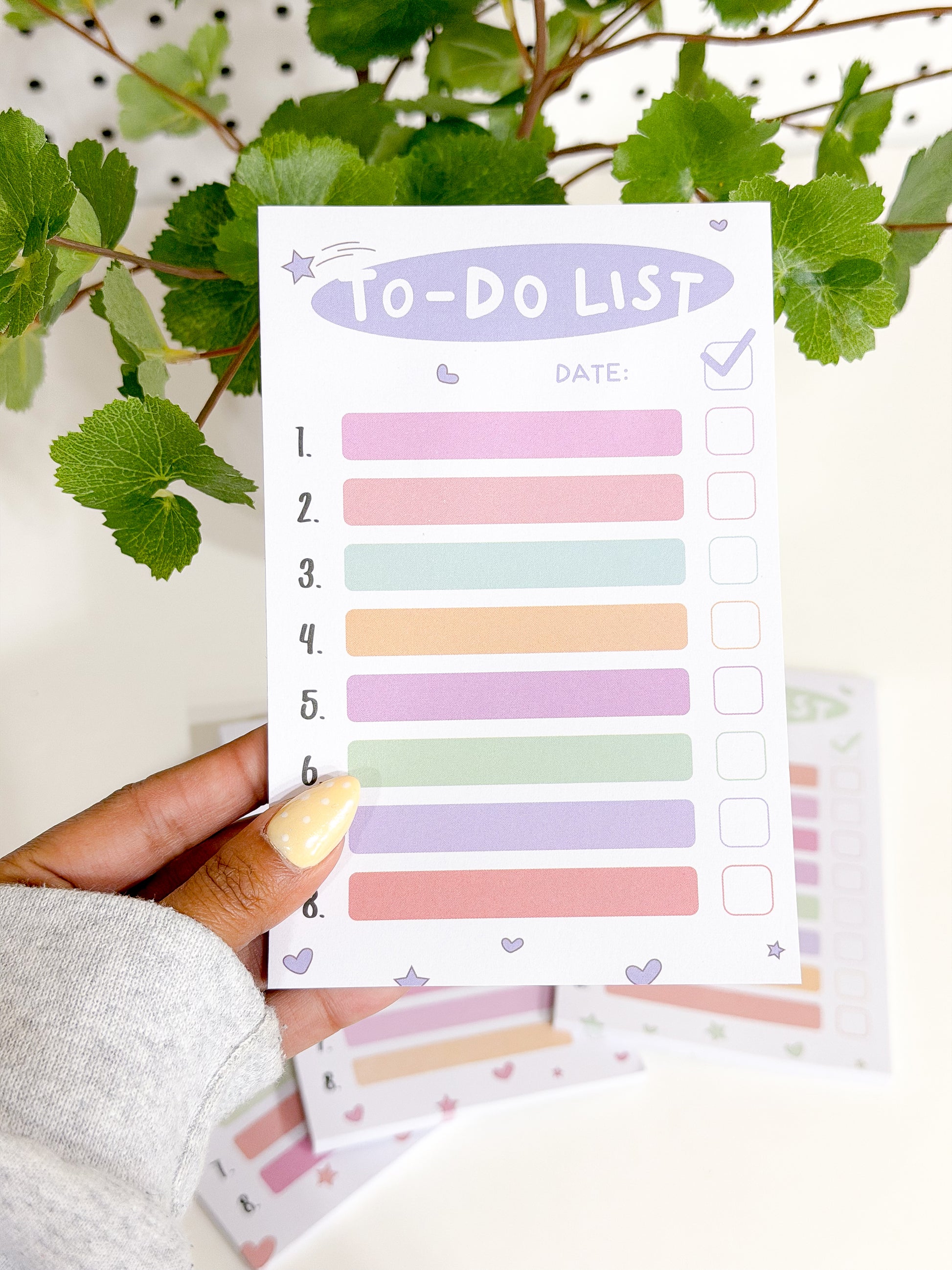 Pastel Tasks Notepad featuring a 'TO-DO LIST' title, numbered lines, and colorful task boxes, held by a hand with polka-dot nail polish.