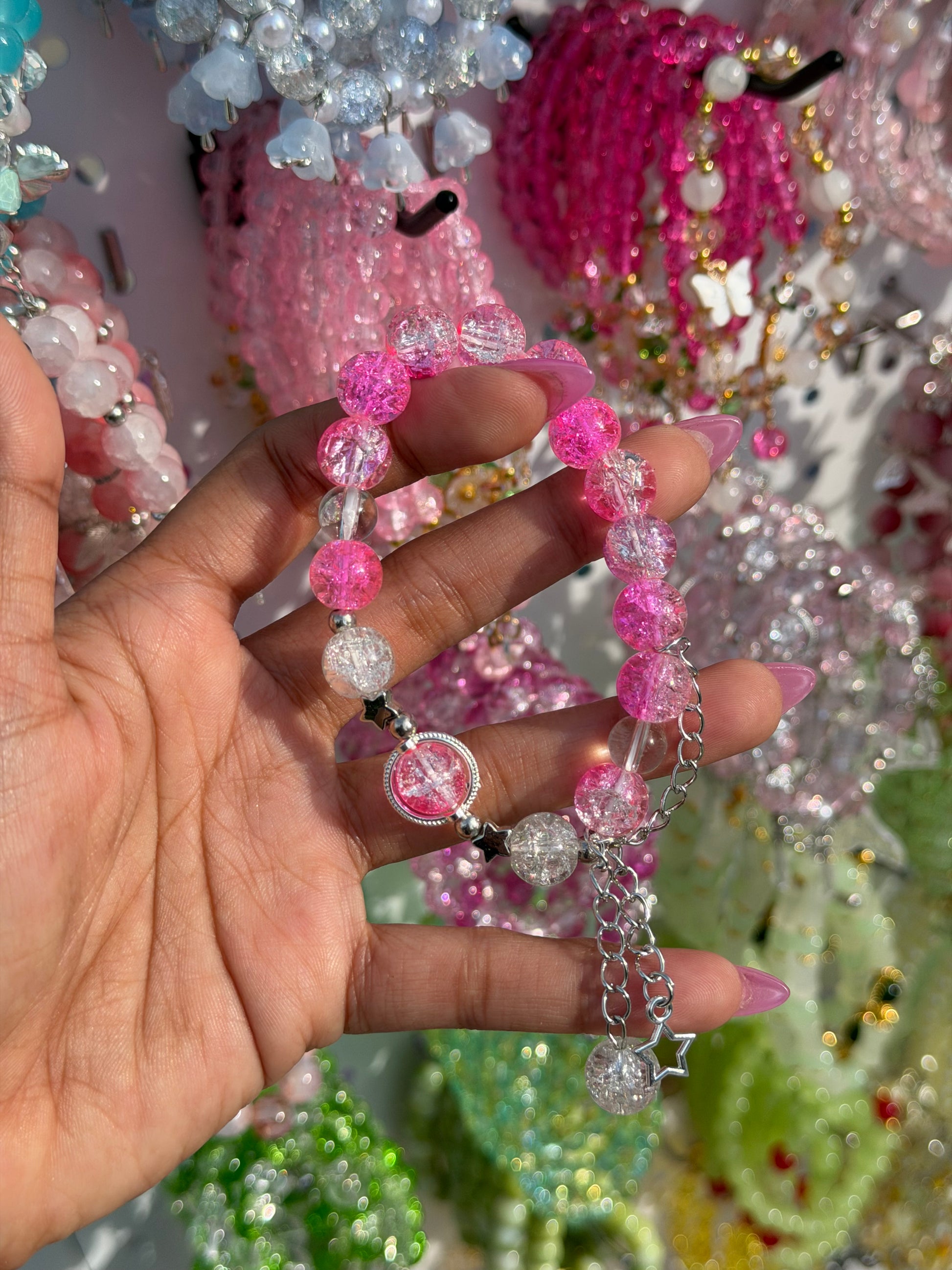 Pink Star Crystal Beaded Bracelet with pink and clear cracked beads, silver star charms, and chain, held by a hand.