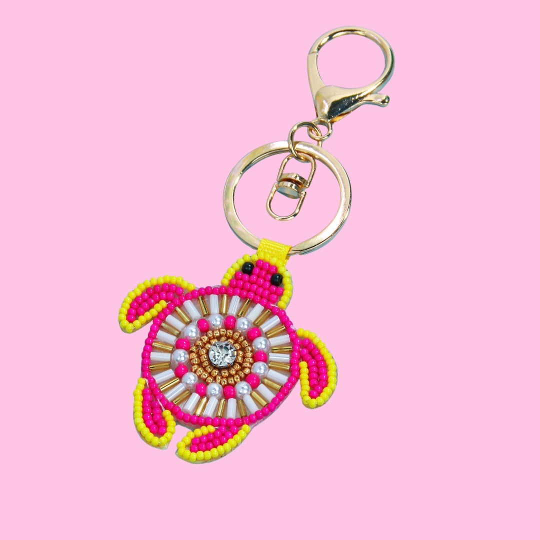 Pink and yellow beaded turtle bag charm with gold clasp and intricate shell design featuring a central clear gem.