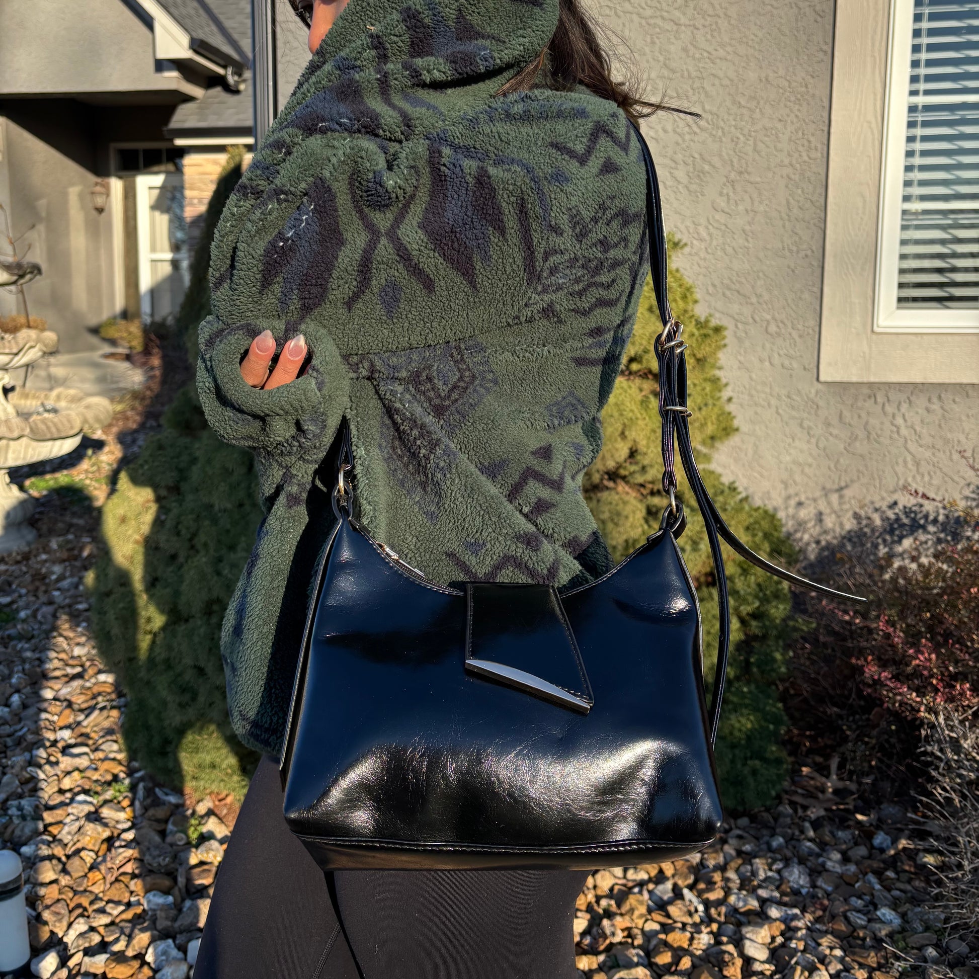 Black shoulder bag by Blaine, featuring a glossy finish and silver-tone hardware detail.