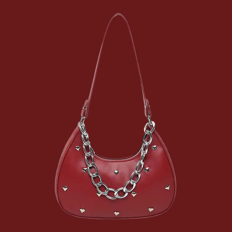 Red handbag with silver chain detail and heart accents, displayed on a red background.