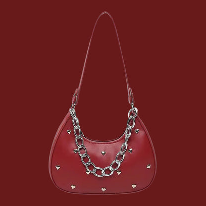 Red handbag with silver chain detail and heart accents, displayed on a red background.