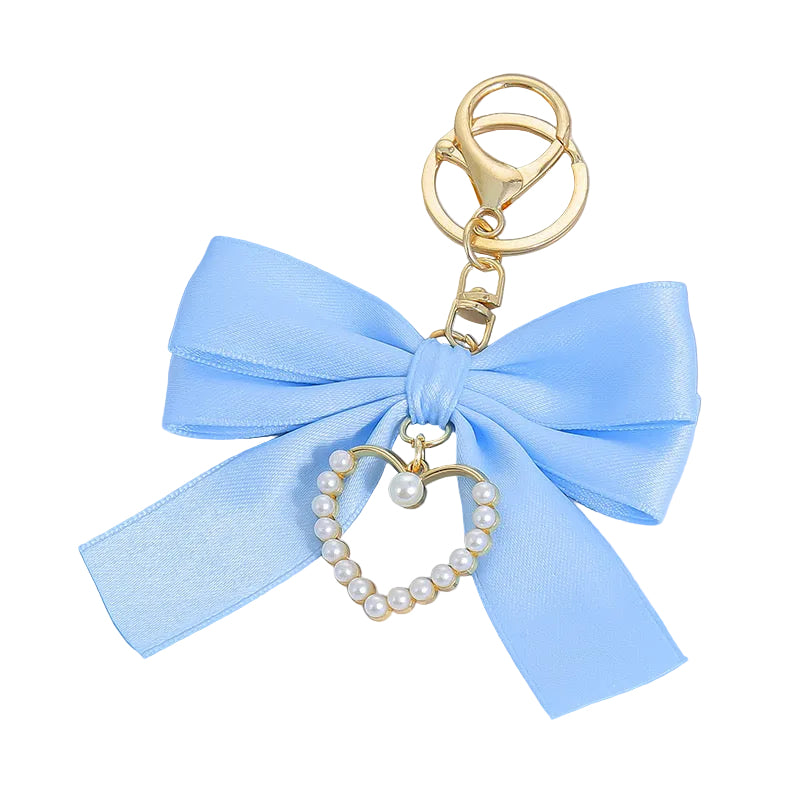 Coquette pearl bag charm with a light blue satin bow and a gold heart charm outlined in pearls.