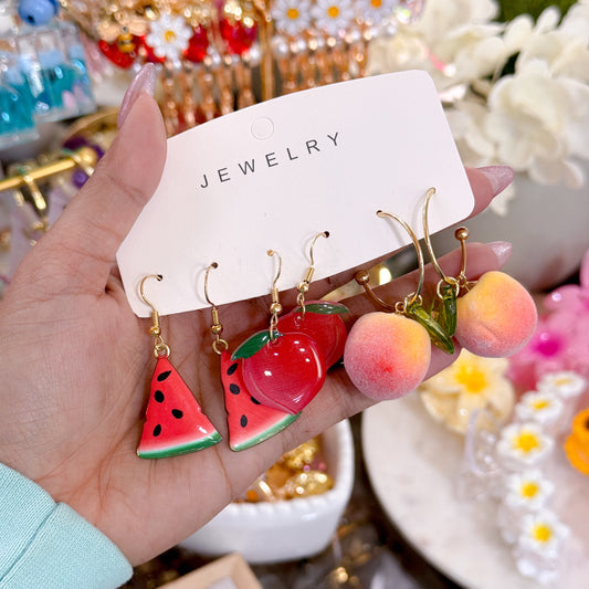 Novelty fruit earrings featuring watermelon slices, cherries, and peach charms on gold hooks.